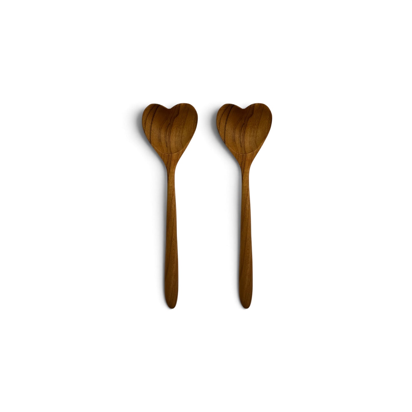 Pair of hand-carved heart-shaped teak wood spoons side-by-side on a clean white background.