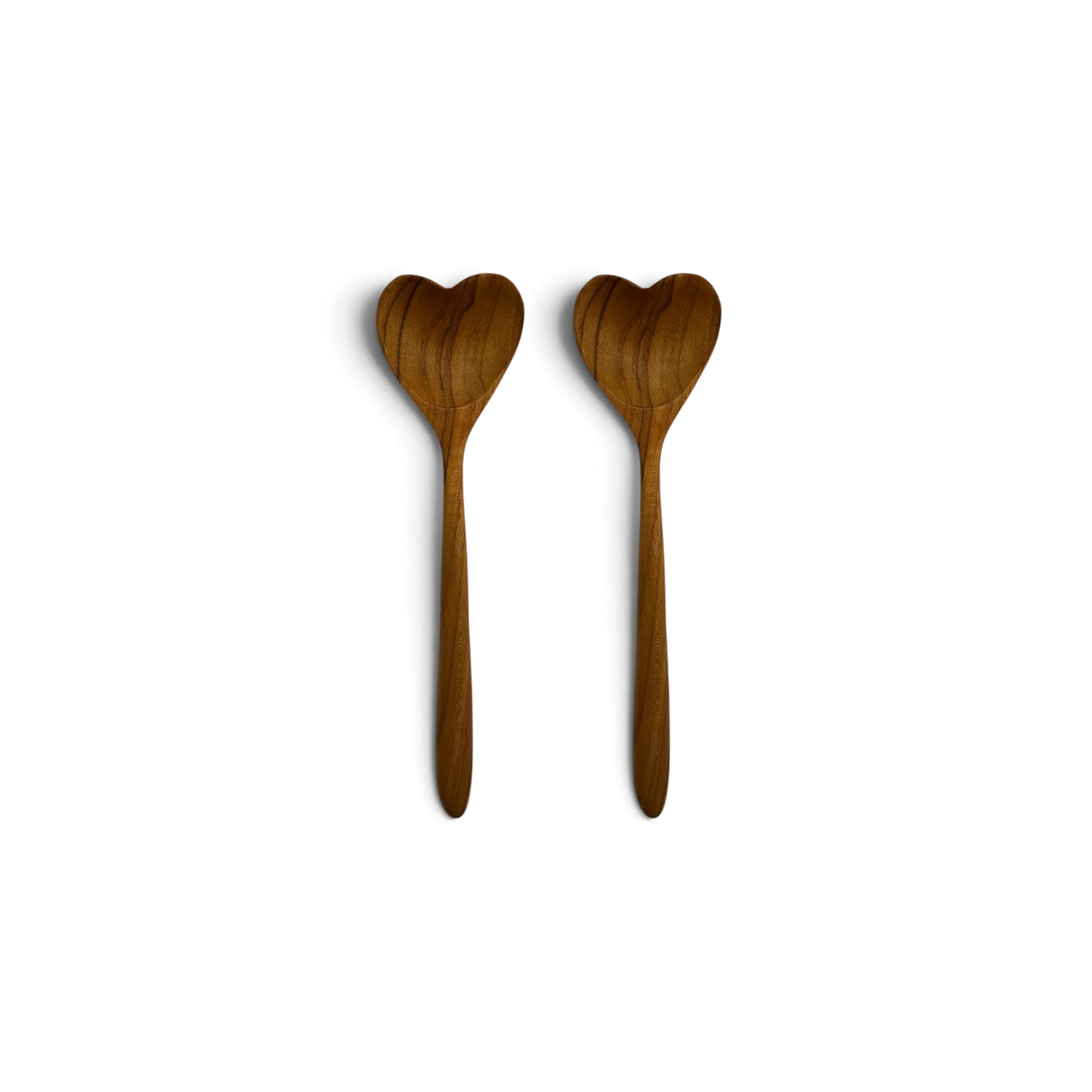Pair of hand-carved heart-shaped teak wood spoons side-by-side on a clean white background.