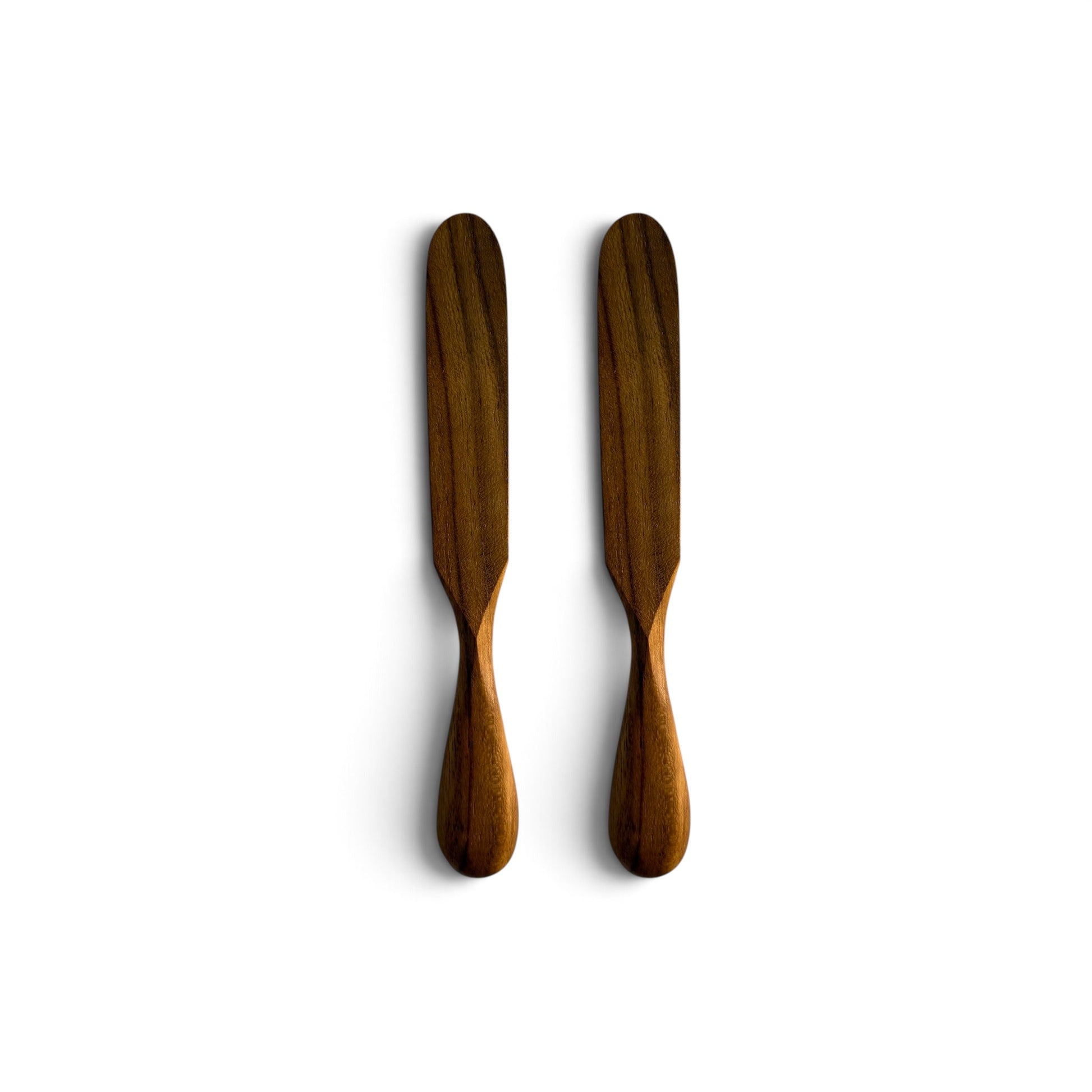 Pair of hand-carved teak wood butter knives with teardrop handles side-by-side on a white background.