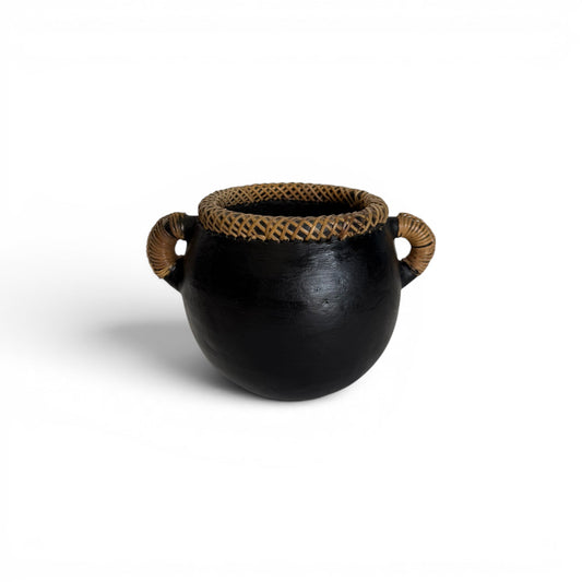 Compact round matte black terracotta decorative pot featuring a hand-woven cross-hatched natural rattan rim collar and two matching coiled loop side handles.