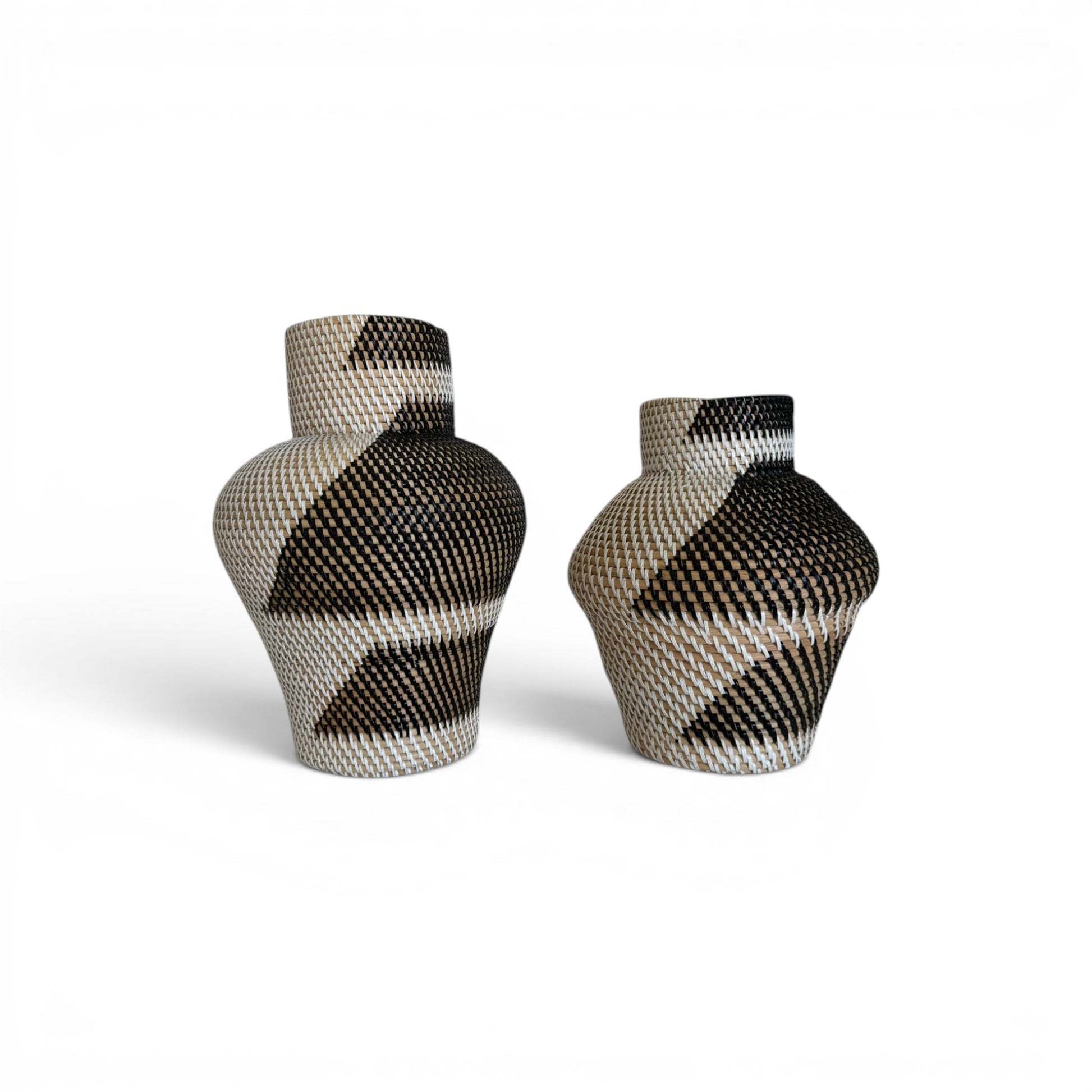 Two geometric hand-woven rattan vases featuring a high-contrast black, cream, and tan graphic tribal pattern with a narrow neck and wide shoulders.
