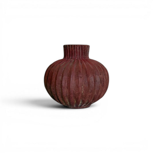 Compact, round earthy red terracotta vase with dense vertical fluted ridges running from the base up through the short neck to the rim.
