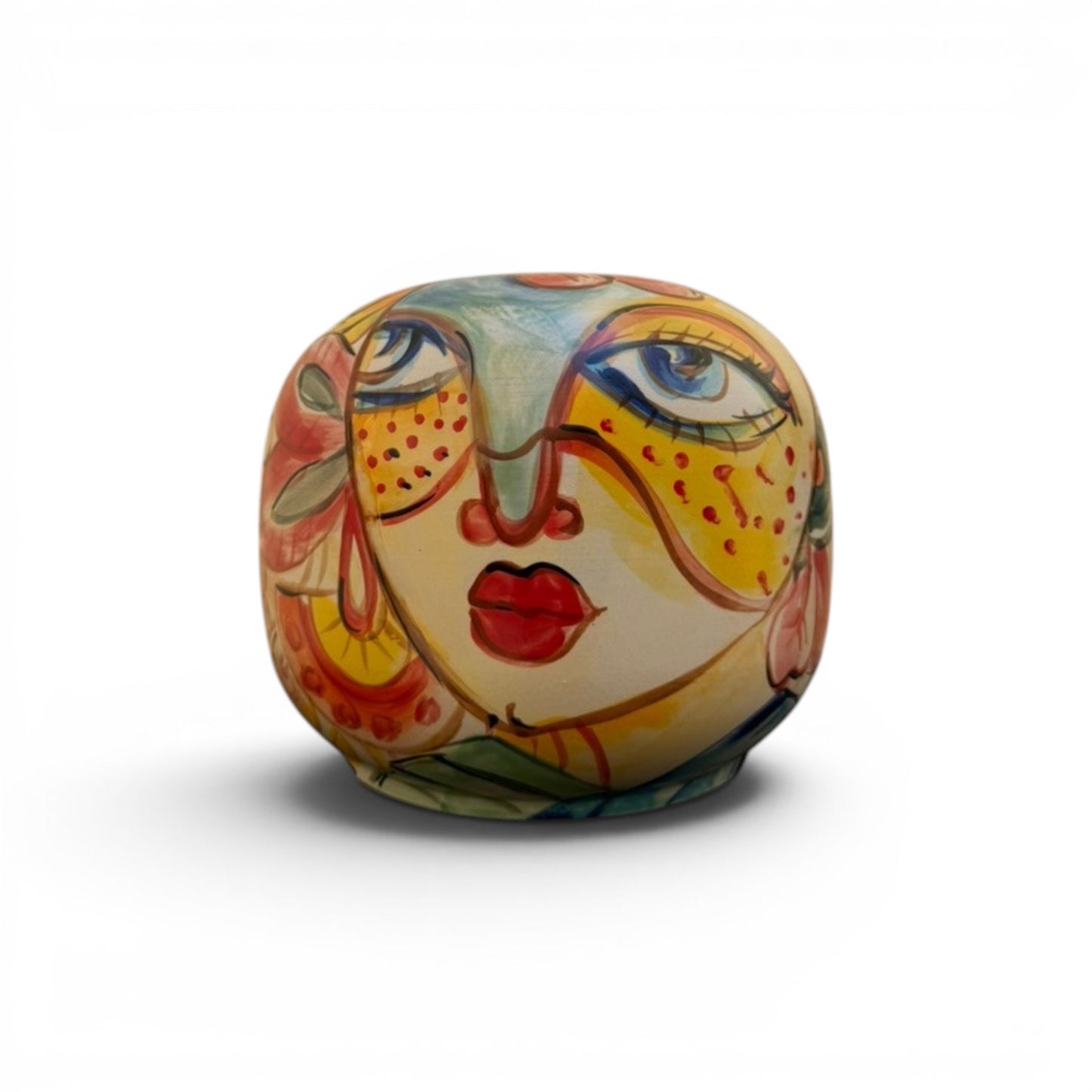 A round ceramic handmade vase like a stylized face, decorated with vibrant hand-painted patterns in yellow, orange, red, blue, and green on a white background.