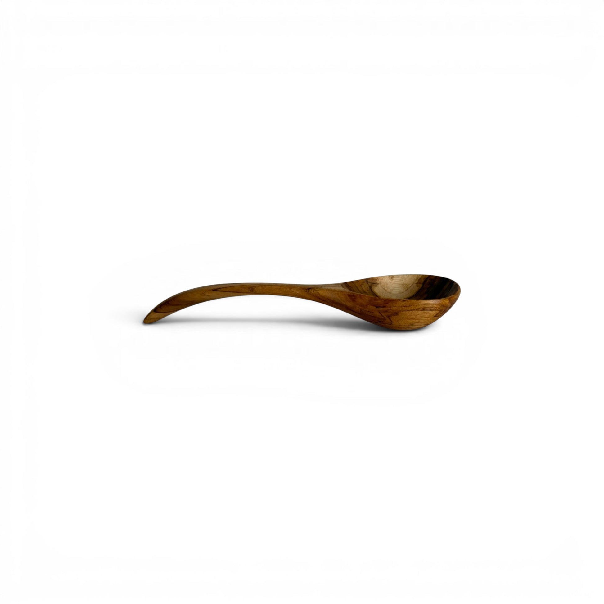 Side profile view of a hand-carved teak wood serving spoon showing an arched handle and deep scoop.